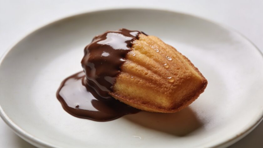Madeleine trempee dans chocolat fondu sur assiette