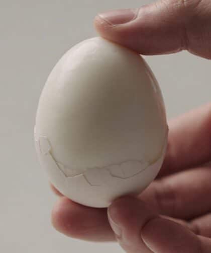 Main en gros plan tenant un oeuf dur pelé