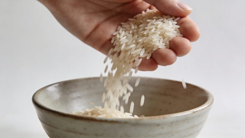 Mains versant du riz sec dans un bol