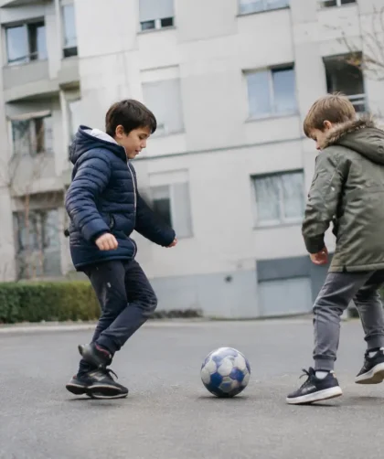 Deux enfants jouant au ballon devant des immeubles