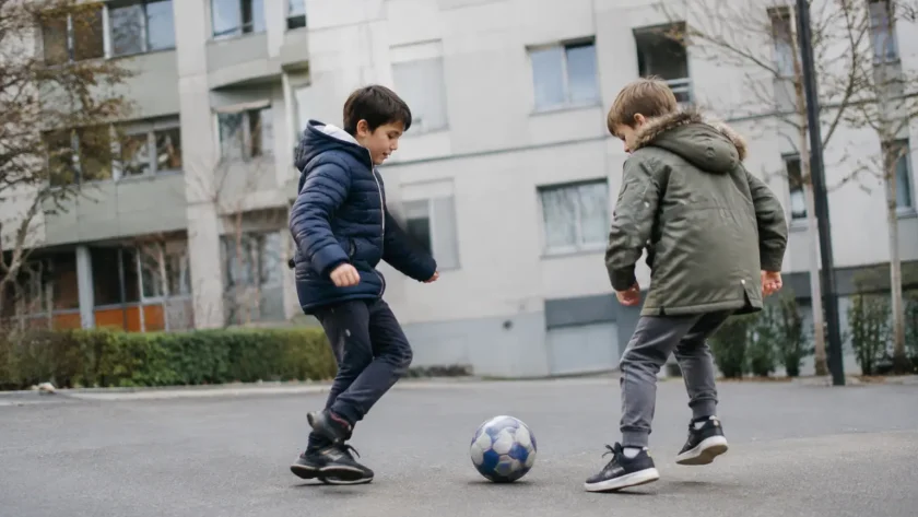 Deux enfants jouant au ballon devant des immeubles