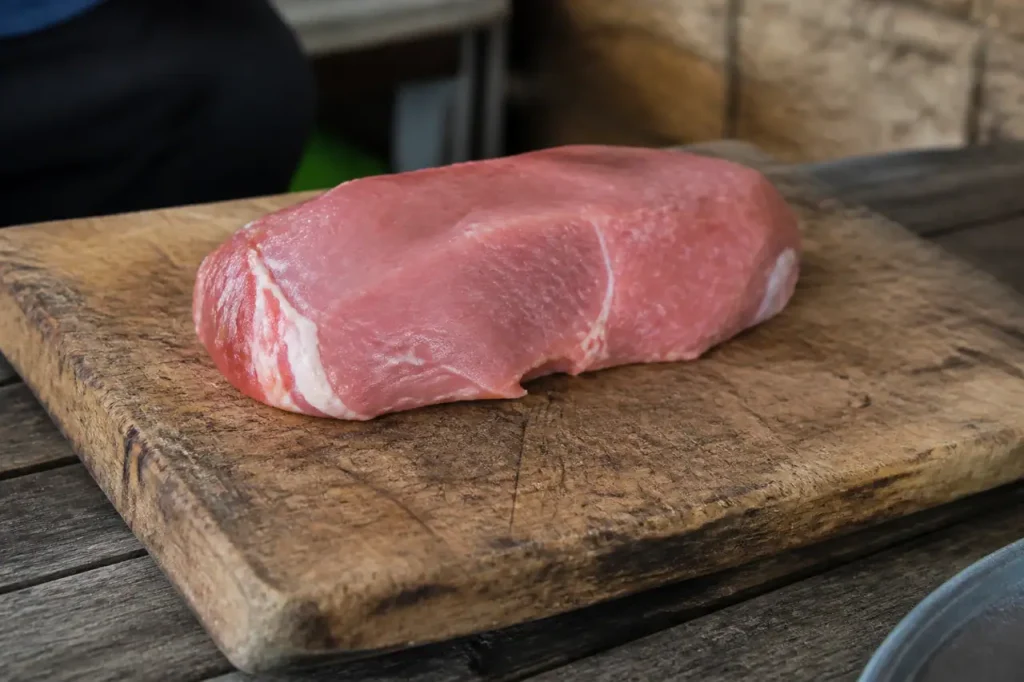Tranche de viande rose posee sur planche bois