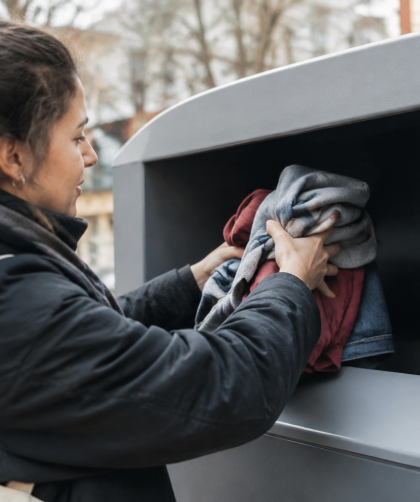 Mains placant vetements dans bac gris recyclage textile