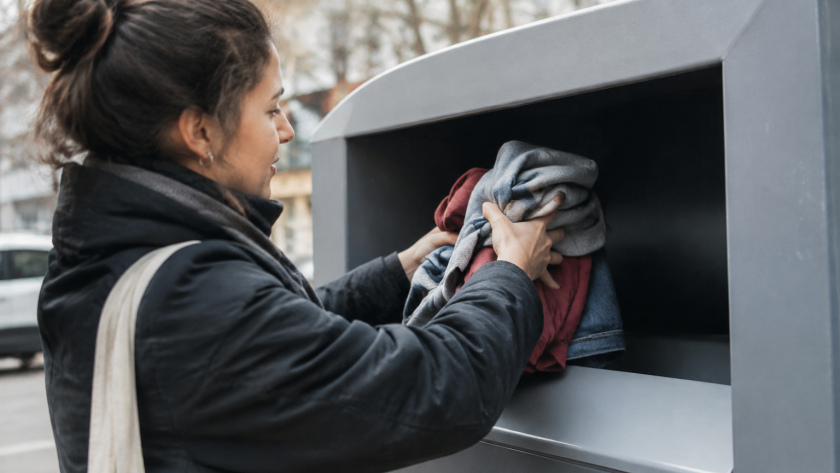 Mains placant vetements dans bac gris recyclage textile