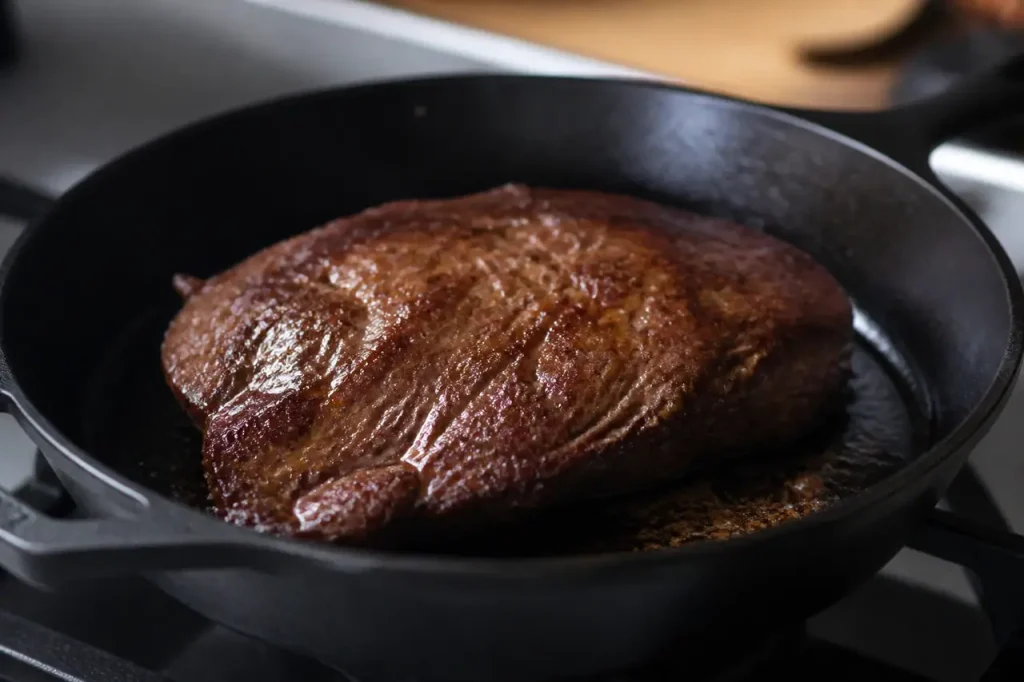 Viande brune luisante sur plat en fonte noire