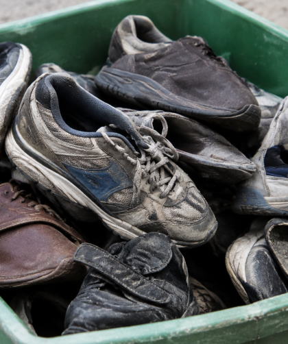Vieilles chaussures usagees entassees dans un bac vert