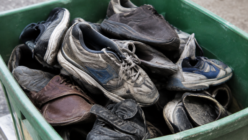 Vieilles chaussures usagees entassees dans un bac vert
